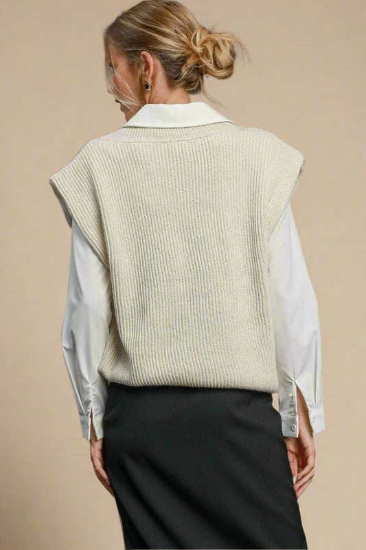Person wearing a cream knit vest over a white shirt with a beige background