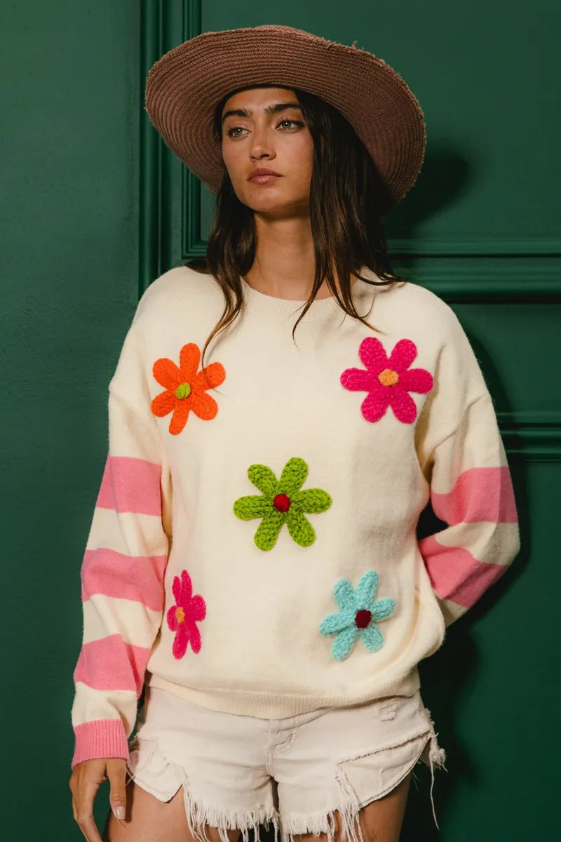 Woman wearing a sweater with colorful flower patterns against a green background