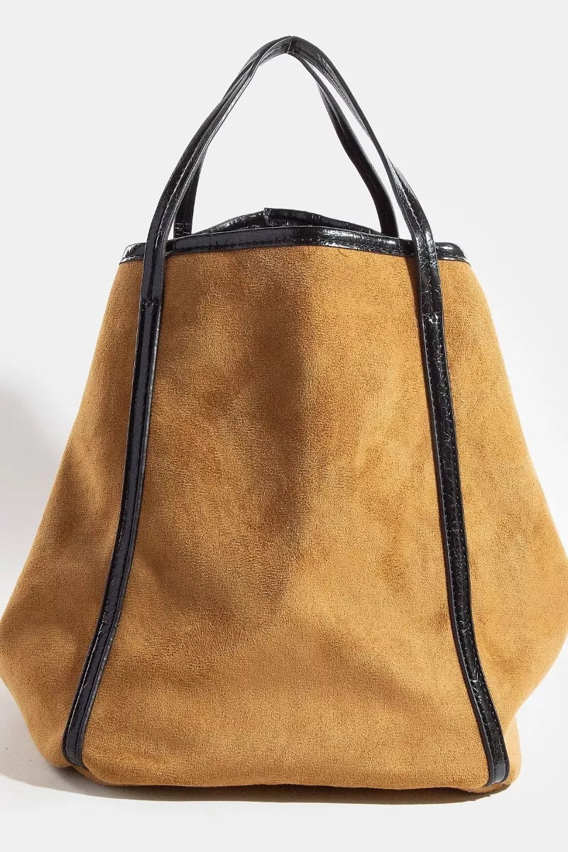 Brown suede handbag with black accents on a white background