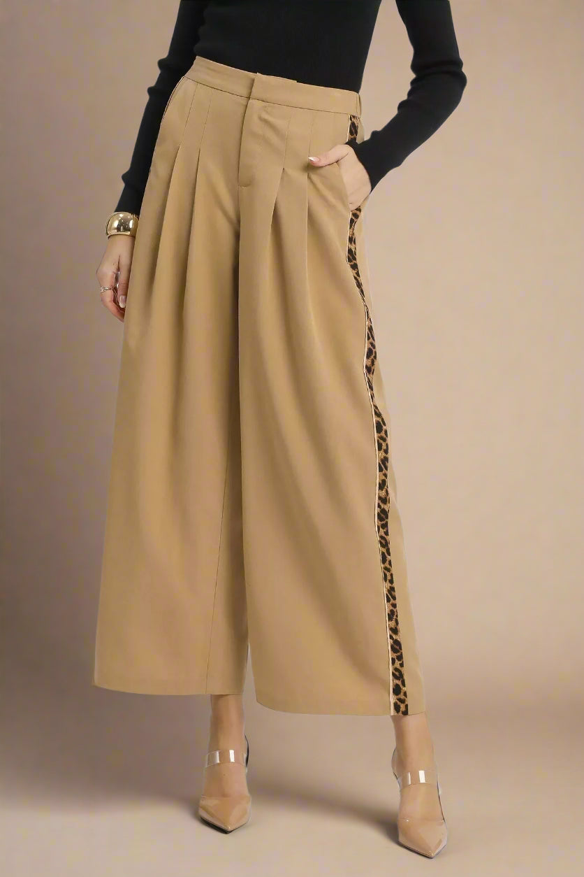 Beige wide-leg pants with leopard print side panels worn by a person on a white background.