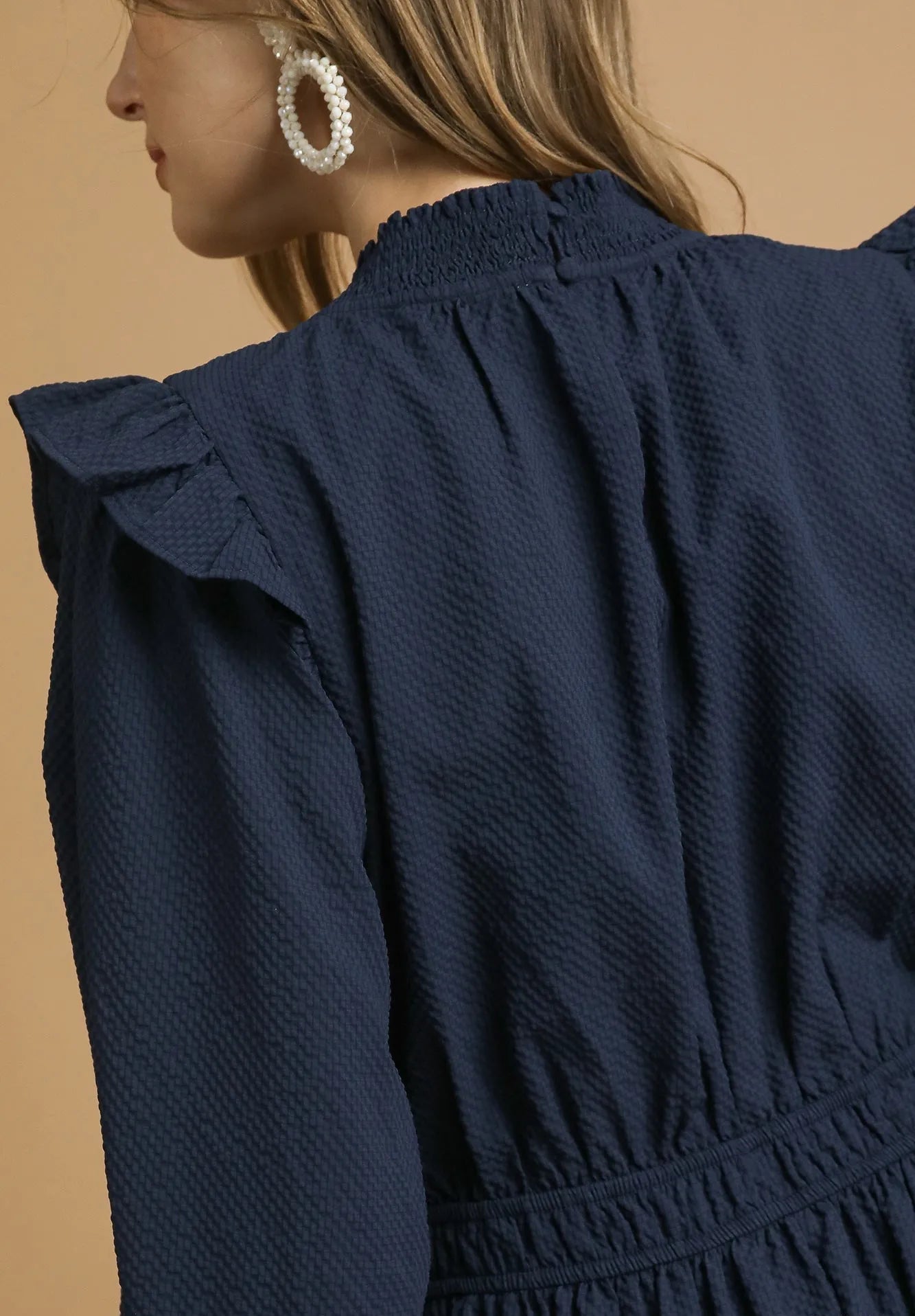 Navy blue dress with ruffled shoulders on a beige background