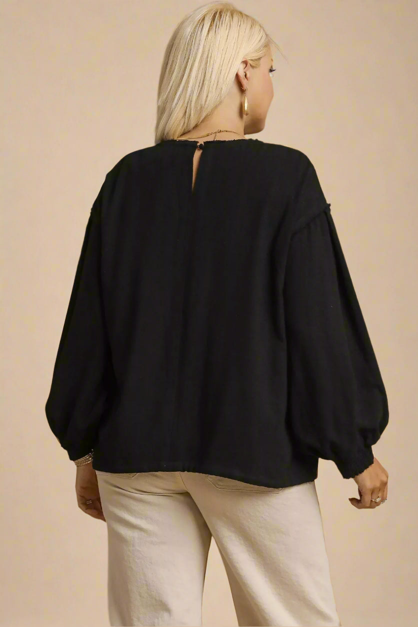 Person wearing a black plus-size top on a beige background