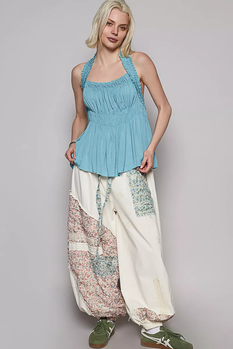 Woman wearing a blue top and patterned pants on a gray background