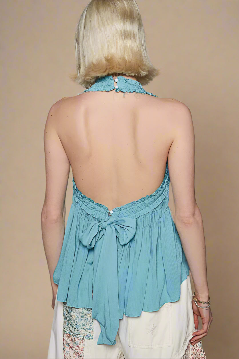 Woman wearing a light blue halter top with a plain background
