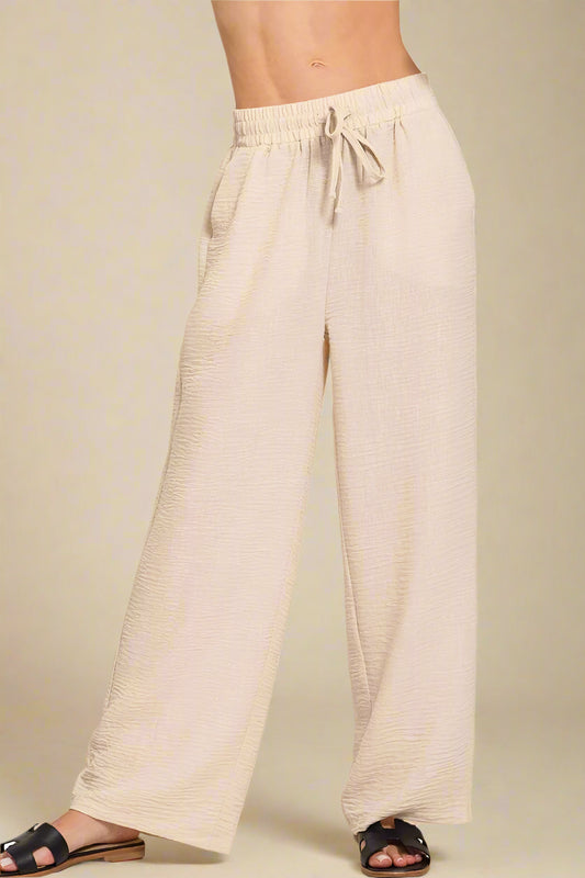 Beige wide-leg pants with a drawstring waist on a beige background
