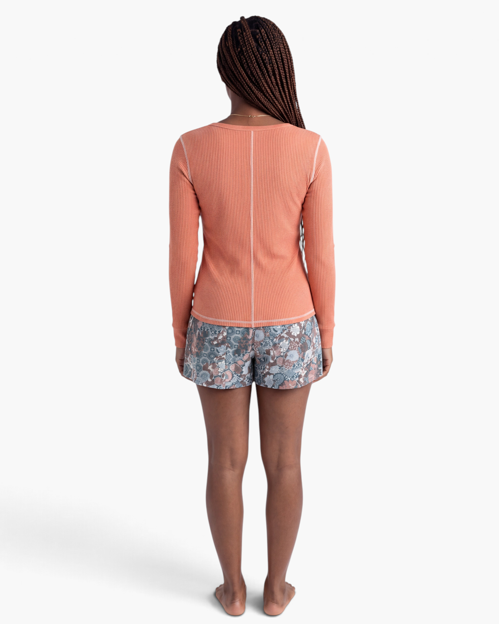 Back view of Beach Rose Co. coral ribbed long sleeve top with contrast seams worn with patterned shorts.