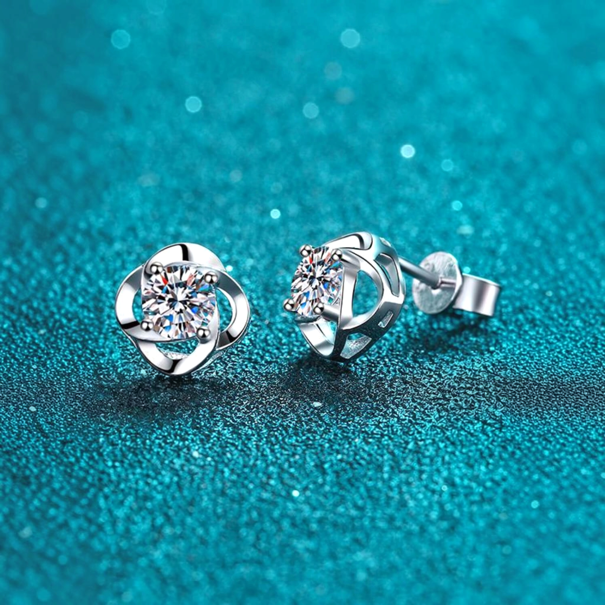 Beach Rose Co. sterling silver flower stud earrings featuring round moissanite stones on a textured teal background.