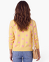 Beach Rose Co. yellow knit cardigan with pink polka dots, long sleeves, and ribbed hem, worn from the back.