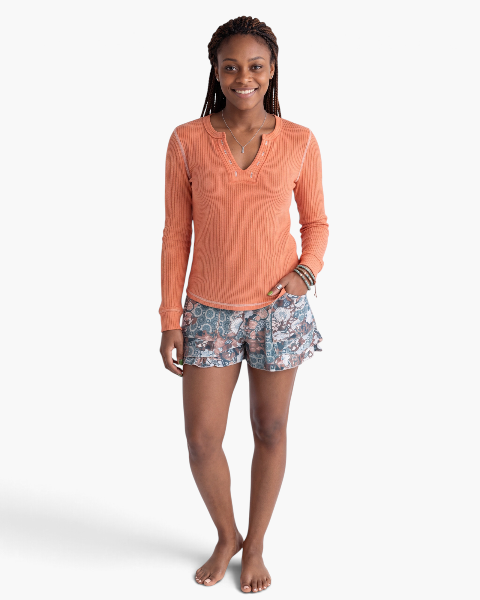 Beach Rose Co. coral ribbed long sleeve V-neck top with contrast stitching worn with patterned shorts.
