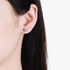Beach Rose Co. heart-shaped moissanite stud earrings in rhodium-plated sterling silver worn on an earlobe.