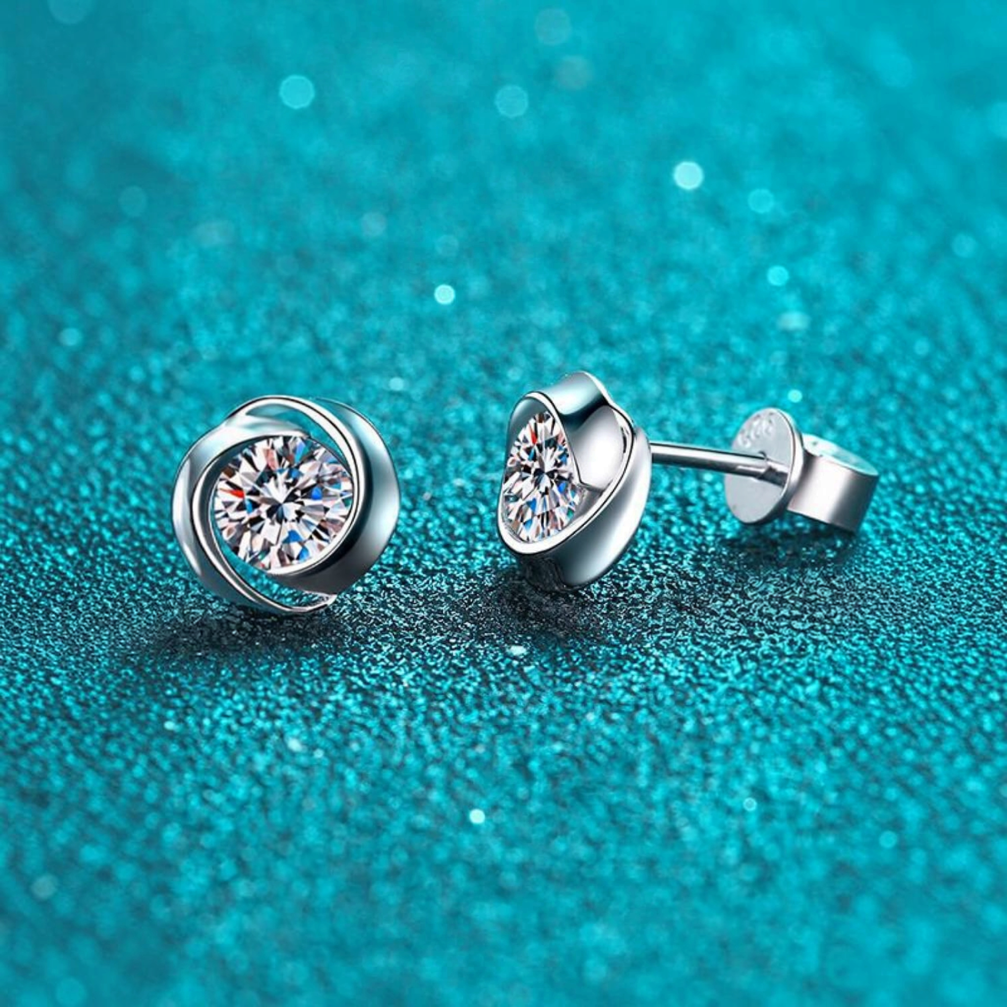 Beach Rose Co. sterling silver stud earrings featuring round moissanite stones in a polished swirl setting.