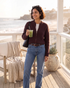 Beach Rose Co. coffee brown zip-up knit cardigan with ribbed trim worn over a white tee and blue jeans on a deck.