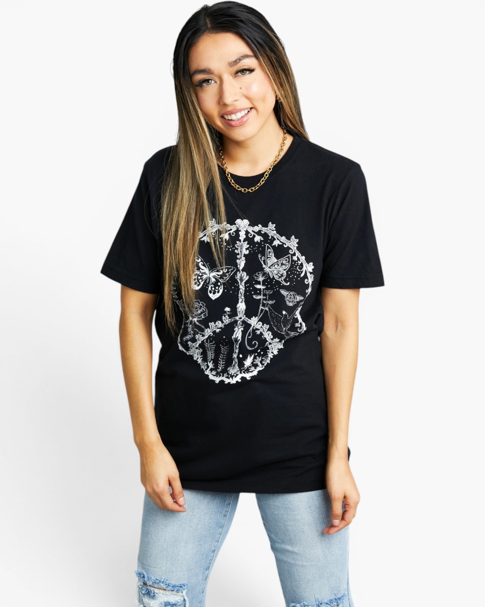 A woman modeling a black short-sleeve t-shirt with a large white graphic print of a crown on the front, paired with light blue jeans, against a plain white background.
