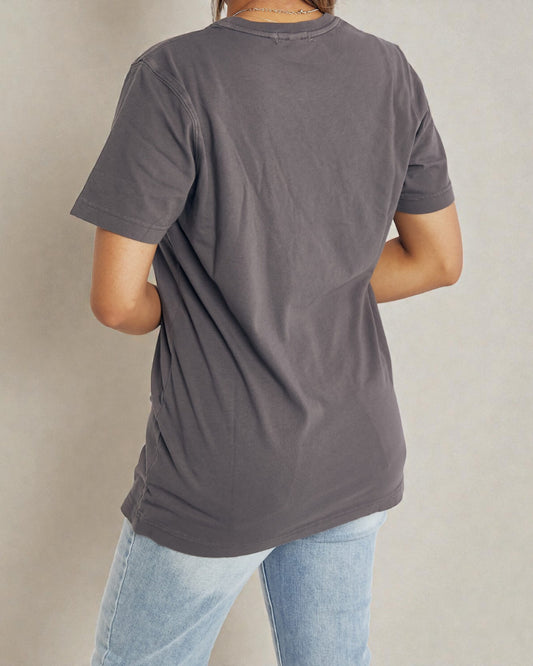 Person wearing a gray t-shirt and light blue jeans against a beige background