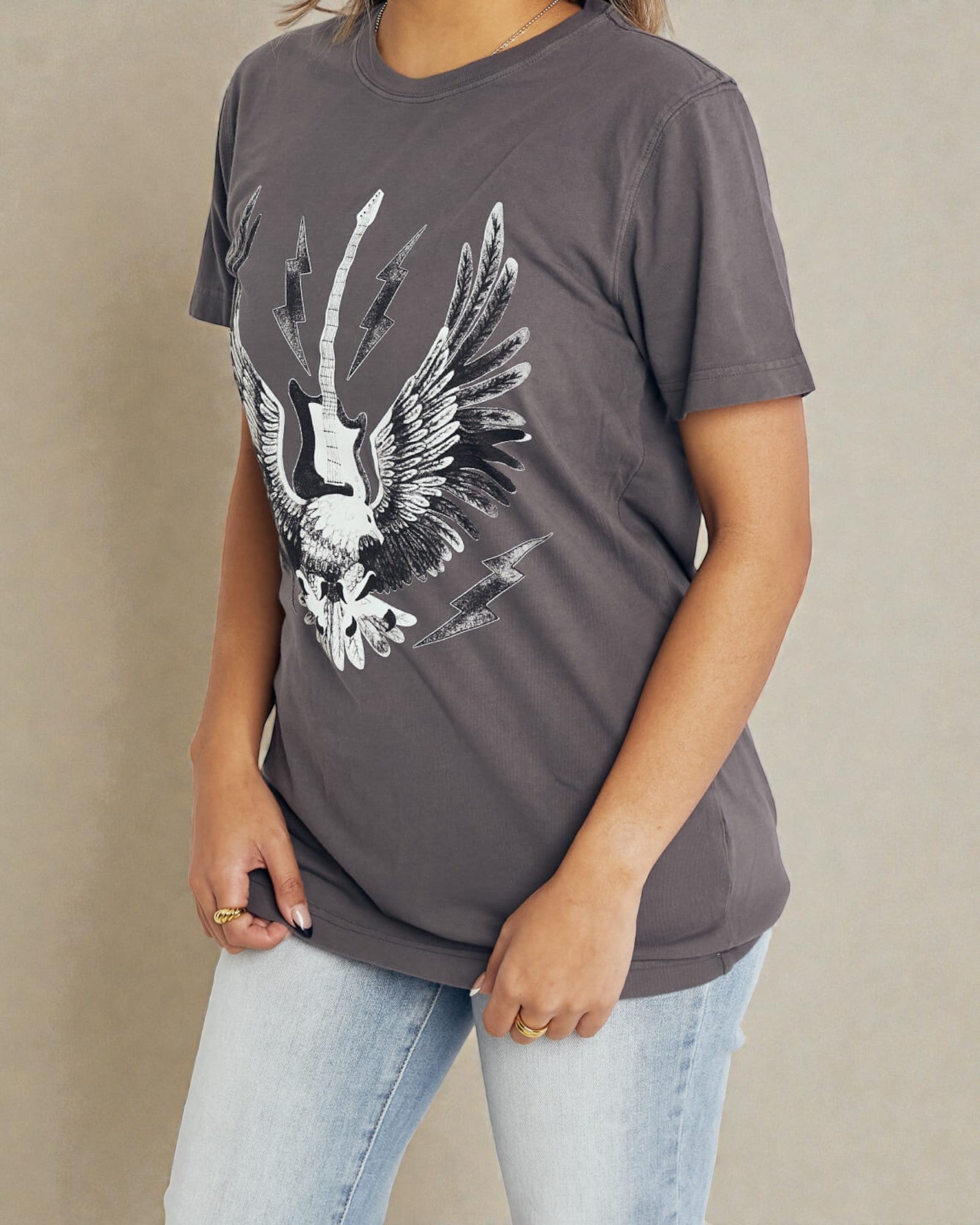 Person wearing a gray t-shirt with an eagle graphic design on a beige background