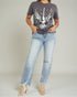 Person wearing a gray t-shirt with an eagle design and light blue jeans on a plain background