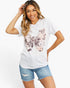 A woman modeling a white short-sleeve crewneck t-shirt with a large butterfly graphic on the front, paired with light-wash denim shorts, against a plain white background.