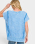 Woman wearing a blue tunic with a plain background