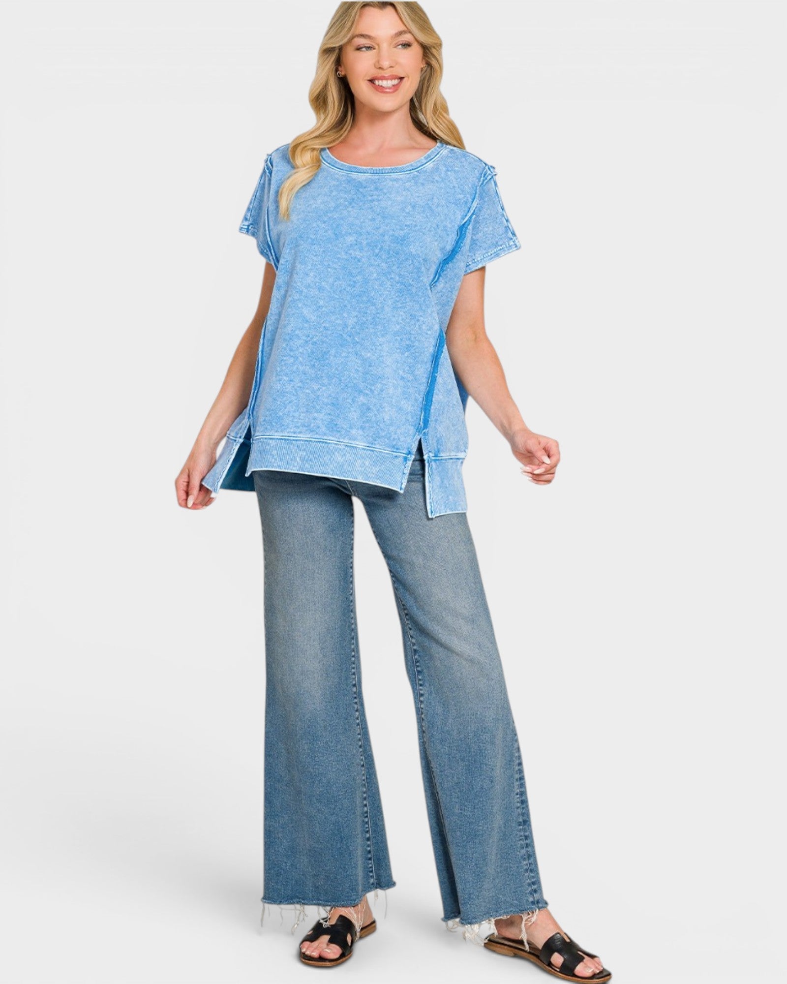 Woman wearing a blue top and denim pants on a white background