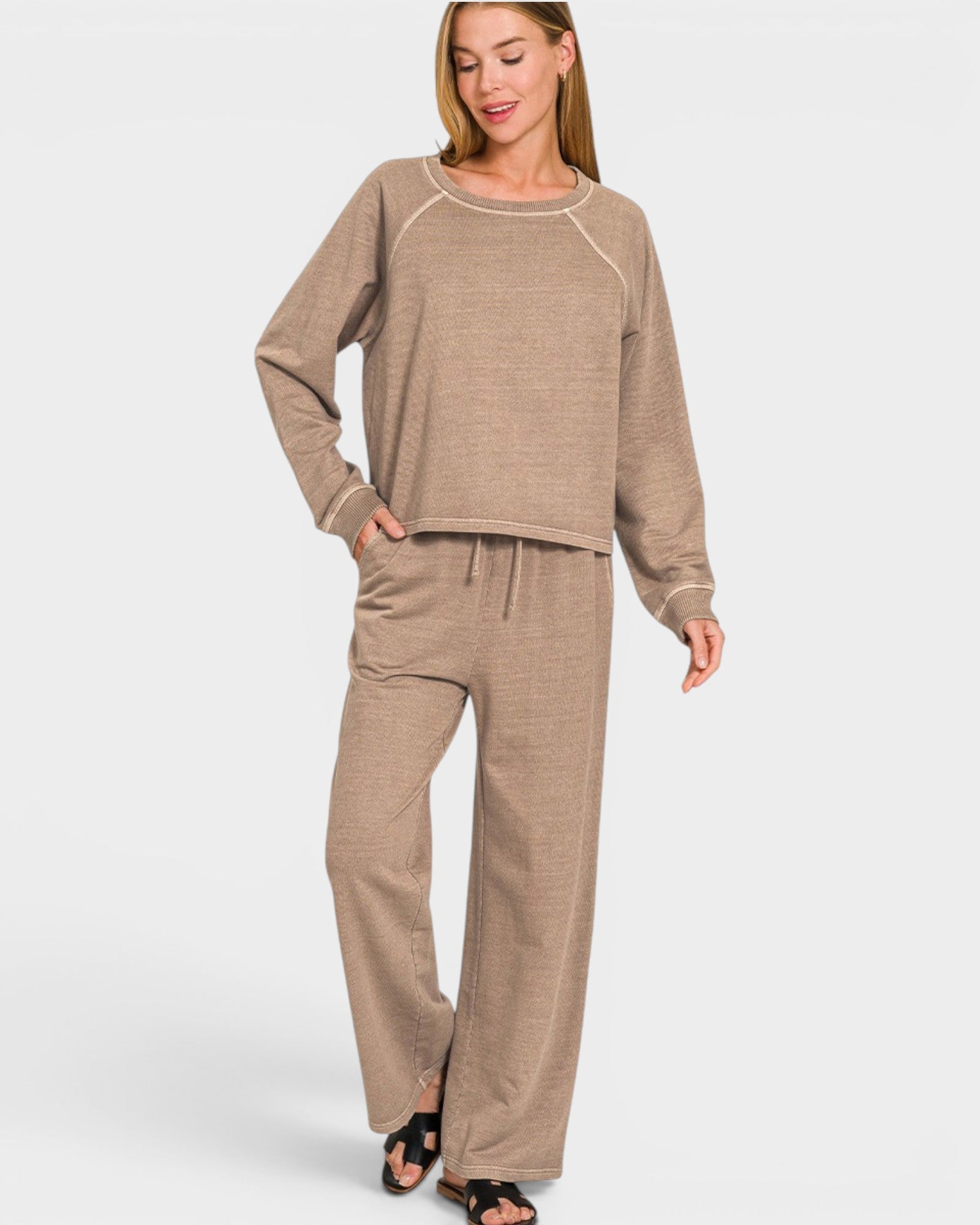 Woman wearing a beige long-sleeve top and pants on a white background