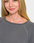 Close-up of a person wearing a gray sweatshirt with a plain background