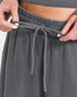 Gray sweatpants with drawstring being adjusted by hands on a light gray background