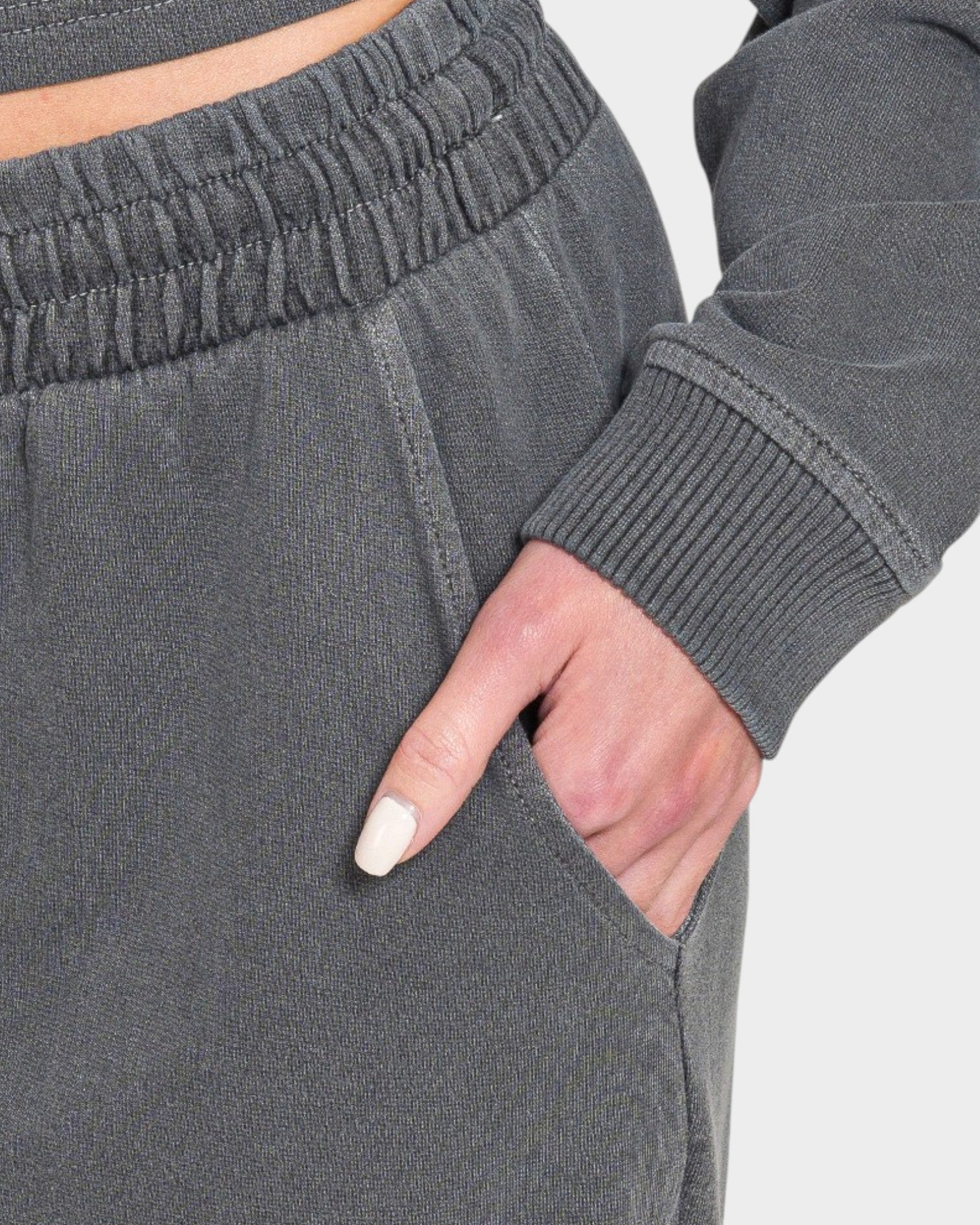 Gray sweatpants with a hand in the pocket on a light gray background
