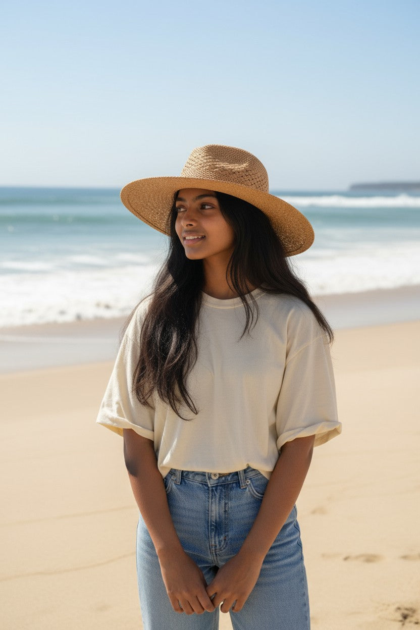 Woman wearing a straw hat on a beach with ocean in the background