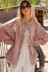 Woman wearing a pink denim jacket and sunglasses in a rustic outdoor setting